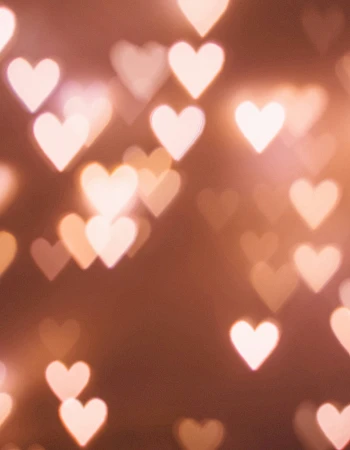 A soft background of warm, glowing heart-shaped bokeh lights scattered across the frame.