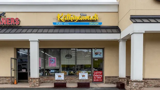 A restaurant storefront reading &ldquo;Kathyawadi Pure Veg Dhaba,&rdquo; with posters in the window and a &ldquo;Coming Soon&rdquo; sign.